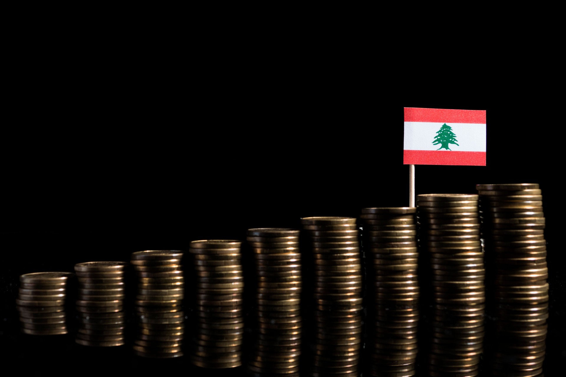 Lebanese flag with lot of coins isolated on black background